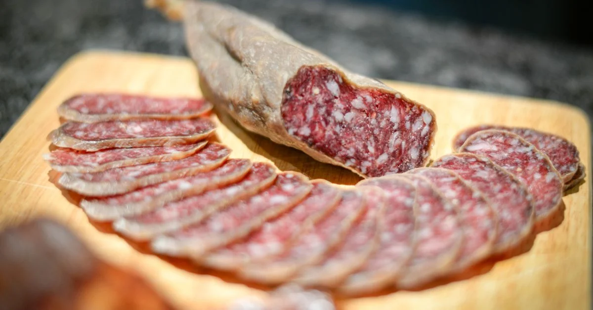 Délicieuses tranches de salami disposées sur une planche à découper en bois, prêtes à être dégustées.