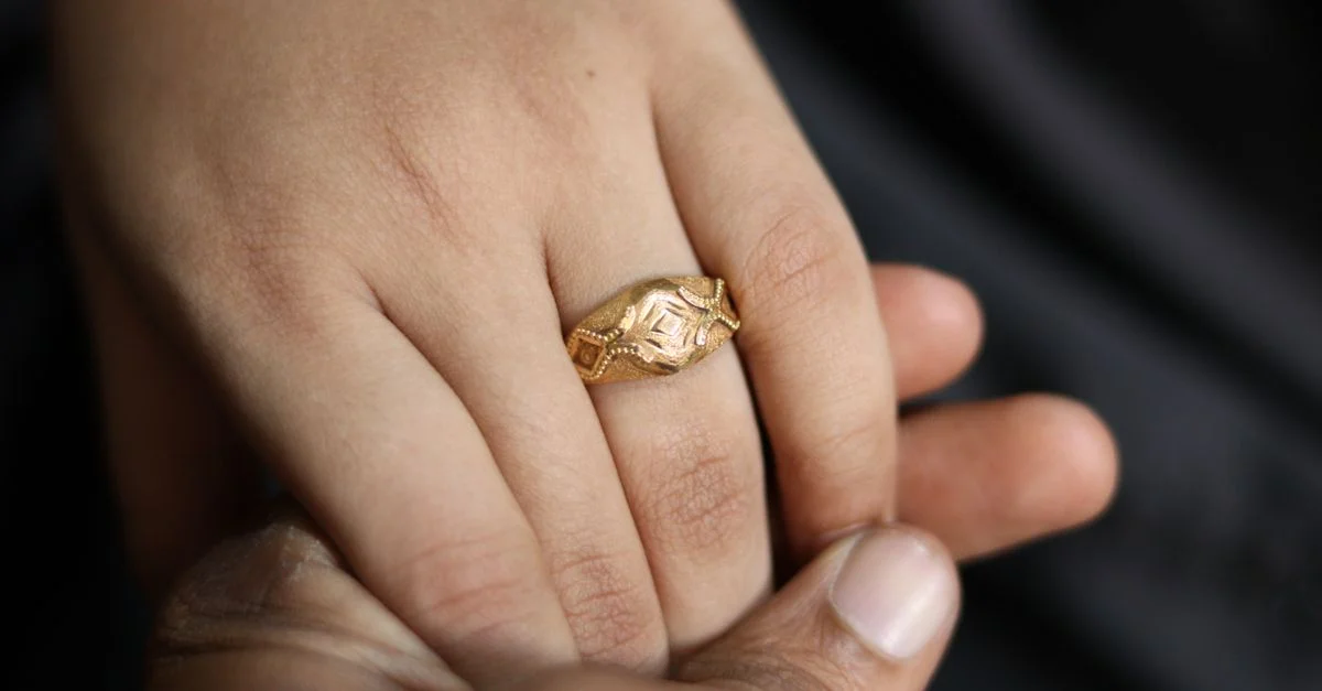 Gros plan intime d'une bague en or sur une main, mettant en valeur le toucher doux et l'élégance.
