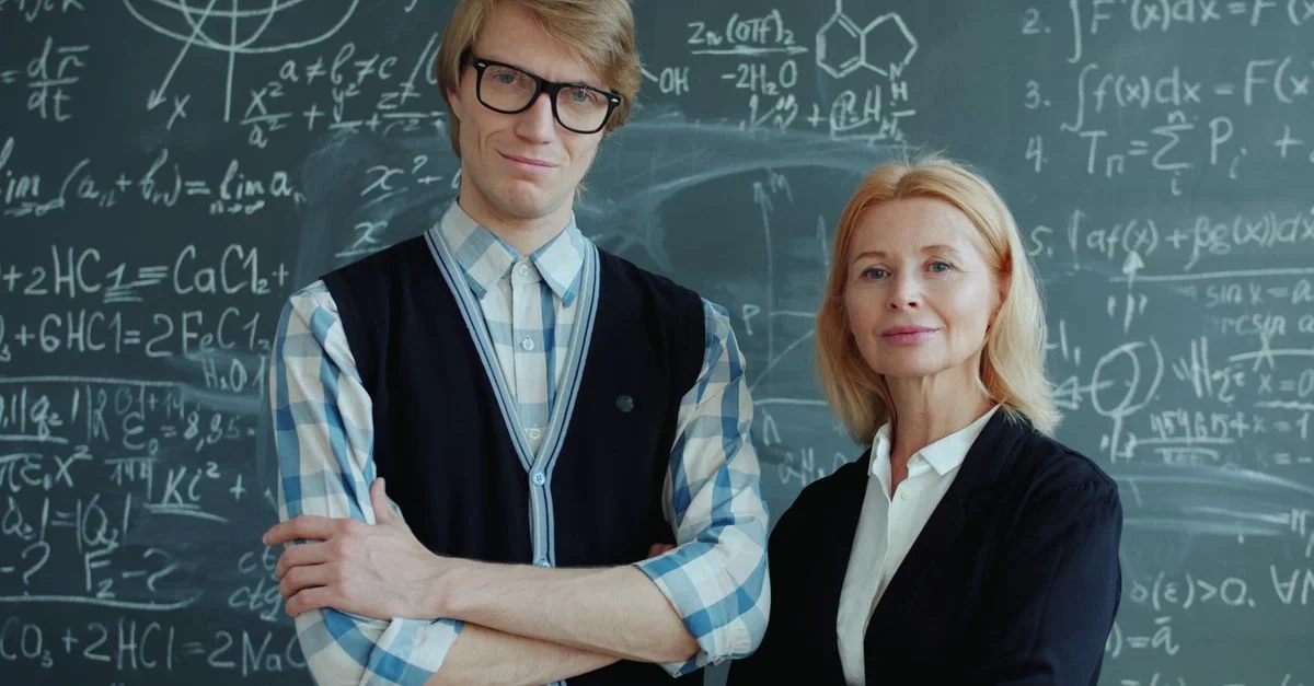 Deux enseignants posent avec assurance devant un tableau noir couvert de mathématiques.