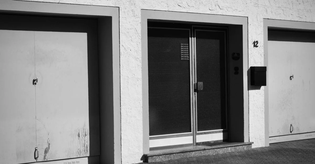 Photo monochrome de la façade d'un immeuble urbain avec garages et portes.