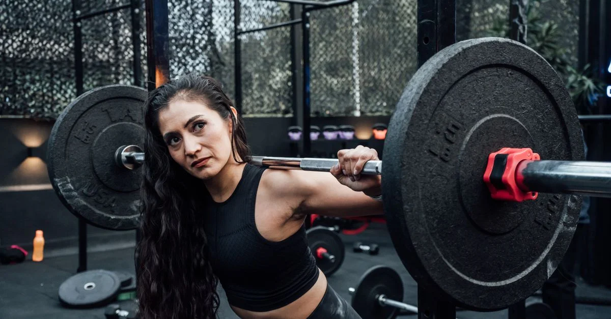 Une femme déterminée soulevant des poids dans une salle de sport moderne, incarnant fitness et force.
